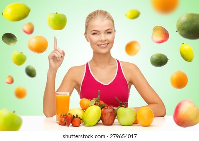 healthy eating, diet, detox and people concept - happy young woman with organic food or fruits pointing finger up over green background with falling fruits