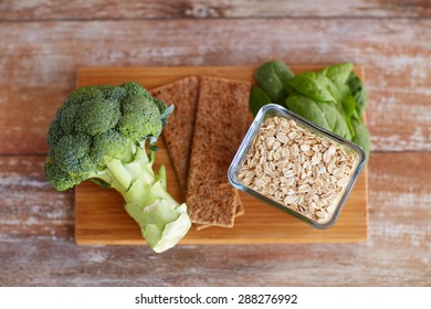 Healthy Eating, Diet And Fiber Rich In Food Concept - Close Up Of Broccoli, Crispbread, Oatmeal And Spinach On Wooden Table