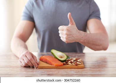 healthy eating, diet, gesture and people concept - close up of male hands showing thumbs up with food rich in protein on cutting board on table - Powered by Shutterstock