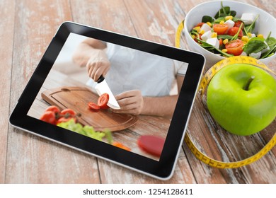 healthy eating, diet and technology concept - close up of tutorial cooking video on tablet computer screen, green apple, measuring tape and salad - Powered by Shutterstock