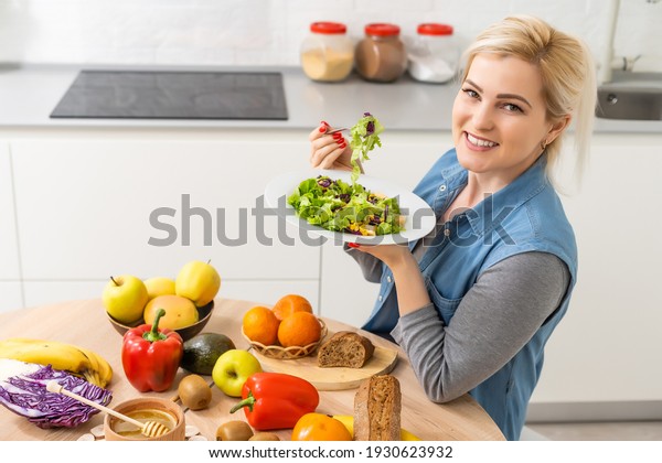 healthy eating, dieting and\
people concept - close up of young woman eating vegetable salad at\
home