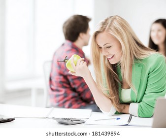 Healthy Eating And Education Concept - Picture Of Smiling Student Girl Eating Apple At School