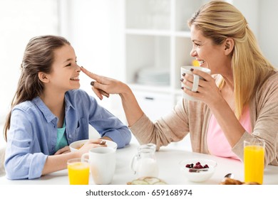 healthy eating, family and people concept - happy mother and daughter having breakfast at home kitchen - Powered by Shutterstock