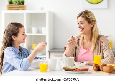 healthy eating, family and people concept - happy mother and daughter having breakfast at home kitchen - Powered by Shutterstock