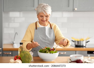 healthy eating, food cooking and culinary concept - happy smiling senior woman making vegetable salad on kitchen at home - Powered by Shutterstock