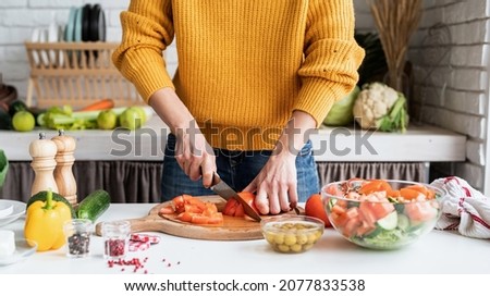 Healthy eating. Front view of female hands making salad cutting tomatoes in the kitchen
