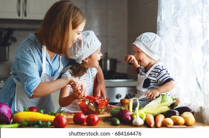 Healthy Eating. Happy Family Mother And Children  Prepares   Vegetable Salad In Kitchen
