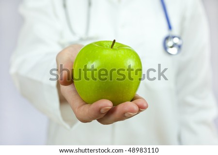Healthy eating or lifestyle concept shot of a doctor holding and offering a green apple