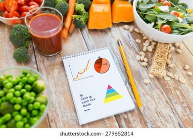 healthy eating, vegetarian food, diet and weight control concept - close up of ripe vegetables and notebook with charts and calories on wooden table