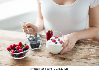 Healthy Eating, Vegetarian Food, Diet And People Concept - Close Up Of Woman Hands With Yogurt, Berries And Poppy Or Chia Seeds On Spoon