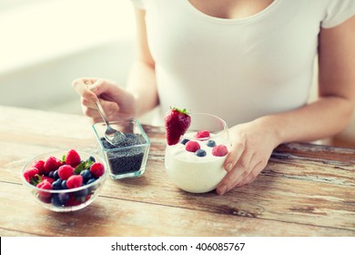 Healthy Eating, Vegetarian Food, Diet And People Concept - Close Up Of Woman Hands With Yogurt, Berries And Poppy Or Chia Seeds On Spoon