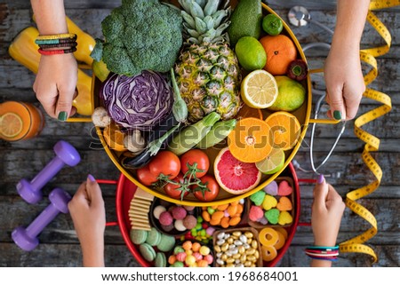 Healthy eating vs unhealthy eating with medicine pills, stethoscope and meter tape on the table. Healty lifestyle concept. 