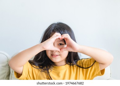 Healthy eyes and vision.Portrait happy asian kid child holding heart shaped hands on eyes.Smiling Girl With Healthy Skin Showing Love Sign. Eye care.Carotene vitamin.Focus, optician doctor, optical.