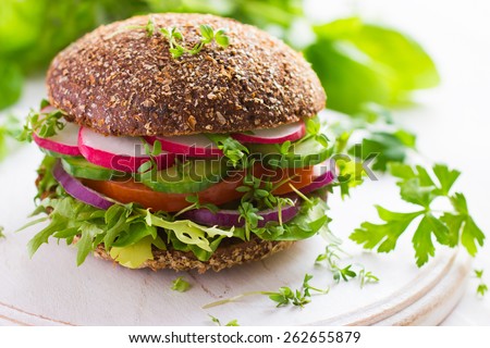 Healthy fast food. Vegan rye burger with fresh vegetables on white wooden  background