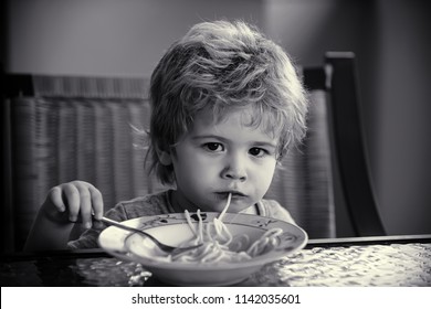 Healthy And Fast Lunch Or Dinner. Serious Child's Look At Camera Eating Spagetti. Independent Kid Eat On His Own With Fork Sitting At The Table. Gluten Free Diet For Children And Gluten Free Products