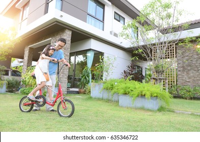 Healthy Father And Daughter Playing Together Outside Their New House. Home Fun  Lifestyle, Family Concept.