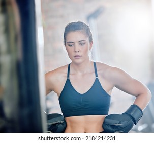 Healthy, fit and active female boxer thinking about a fight, competition or match in the gym or health club. Young woman training, exercising and working out in a fitness studio and looking - Powered by Shutterstock