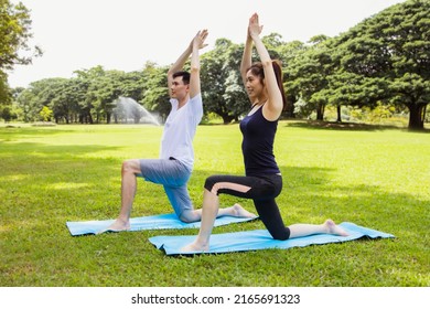 Healthy and fit Asian couple practice yoga stretching outdoors together in the expansive lawn lush green park : Recreational sports and health care concept - Shutterstock ID 2165691323