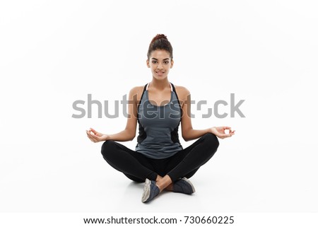 Healthy and Fitness concept - Beautiful American African lady in fitness cloth doing yoga and meditation. Isolated on white background.