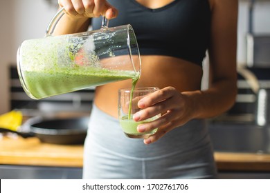 Healthy Fitness Diet Concept. Sporty Woman Serving A Green Detox Smoothie For Breakfast In The Kitchen.