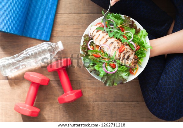 Healthy and fitness food. Chicken salad dish\
with fitness equipments
