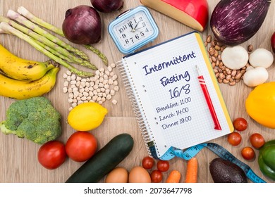 Healthy food around a clock and a notebook with a 16-8 intermittent fasting meal schedule. Concept of intermittent fasting, a diet with benefits such as the regeneration mechanism of autophagy.