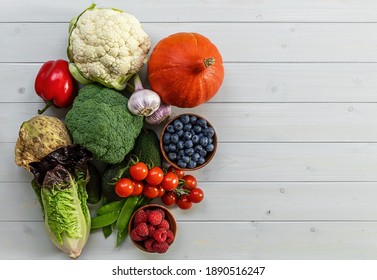 Healthy food background, trendy plant based diet products - fresh raw vegetables and berries. natural wooden table, copy space - Shutterstock ID 1890516247
