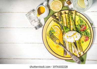 Healthy food, baked grilled asparagus, poached egg and hollandaise sauce on white wooden background copy space top view