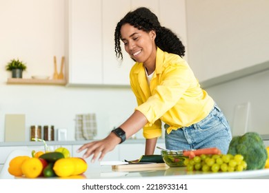Healthy food to boost your immune system. Young african american woman cooking fresh organic salad at home in modern kitchen, reaching for vegetables, free space - Shutterstock ID 2218933141