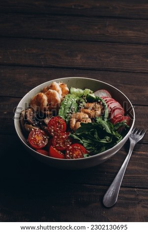 Healthy food. Bowl with shrimp, mushrooms, avocado, arugula, cucumber, cabbage, tomato and radish
