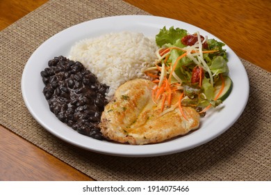Healthy food with chicken breast, beans, rice, vegetable salad on a white plate on wooden table. Brazilian cuisine. - Shutterstock ID 1914075466