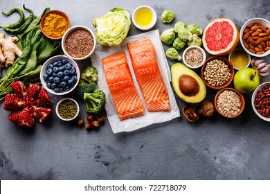 Healthy food clean eating selection: fish, fruit, vegetable, seeds, superfood, cereals, leaf vegetable on gray concrete background copy space