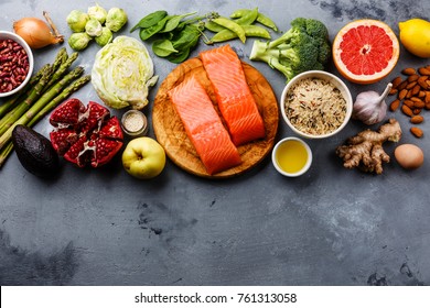 Healthy food clean eating selection: fish, fruit, vegetable, cereal, leaf vegetable on gray concrete background copy space