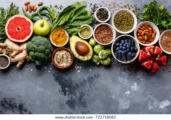 Healthy food clean eating selection: fruit,\
vegetable, seeds, superfood, cereals, leaf vegetable on gray\
concrete background copy\
space