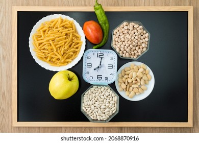 Healthy Food And A Clock On A Blackboard. Conceptual Photograph About Intermittent Fasting, A Diet That Brings Benefits Such As The Regeneration Mechanism Of Autophagy.