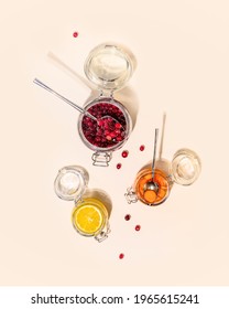 Healthy food composition with glass jars with honey-fermented cranberries, lemon and carrot on a pink background. Homemade natural remedy for colds and to strengthen the immune system. Honey products