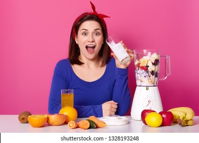 Healthy Food Concept. Close Up Of A Young Woman Uses Berries And Bananas For Making Smoothie. Astonished Lady Againest Pink Studio Wall Drinks Milk While Preparing Coktail. Healthy Lifestyle Concept.