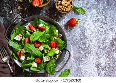 Healthy food concept, Diet salad plate. Summer salad with strawberries, fetacheese and walnut on a stone countertop. Top view flat lay background. Copy space.