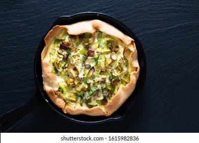 Healthy food concept homemade organic Leek quiche in skillet iron cast on black slate stone board - Powered by Shutterstock