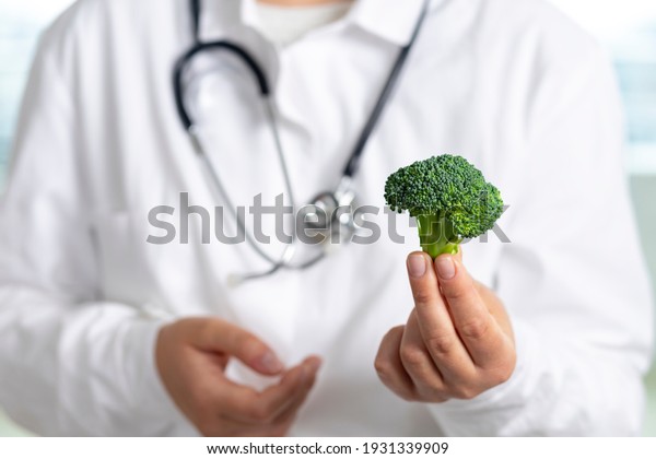 Healthy food concept. Nutritionist doctor holds\
broccoli in his hands