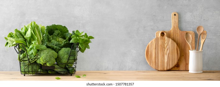 Healthy Food Cooking Concept, Front View On Fresh Green Leafy Vegetables And Kitchen Utensils Standing On Wooden Countertop, Composition With Blank Space