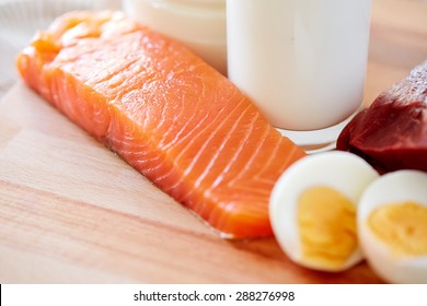 healthy food, culinary, cooking and diet concept - close up of salmon fillets, eggs and milk on wooden table in kitchen