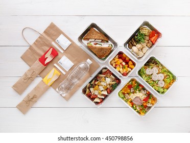 Healthy Food Delivery. Take Away For Diet. Fitness Nutrition, Vegetables, Meat And Fruits In Foil Boxes, Cutlery, Water And Brown Paper Package. Top View, Flat Lay At White Wood With Copy Space