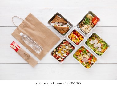 Healthy Food Delivery. Take Away For Diet. Fitness Nutrition, Vegetables, Meat And Fruits In Foil Boxes, Cutlery, Water And Brown Paper Package. Top View, Flat Lay At White Wood With Copy Space