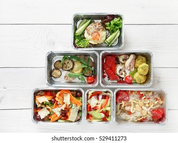 Healthy Food Delivery. Take Away Of Natural Organic Fitness Dishes For Diet. Daily Ratio Nutrition Pyramid Meals In Foil Boxes On White Wood. Top View, Flat Lay