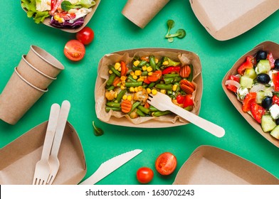 Healthy food in disposable eco friendly food packaging. Steamed vegetables in the brown kraft paper food containers on green background. Top view, flat lay.