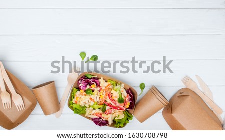 Healthy food in disposable eco friendly food packaging. Vegetable salad in the brown kraft paper food containers on white wooden background with blank space for text. Top view, flat lay.