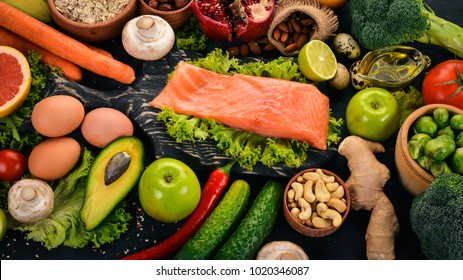 Healthy food. Fish salmon, avocado, broccoli, fresh vegetables, nuts and fruits. On a black background. Top view. Copy space. - Shutterstock ID 1020346087