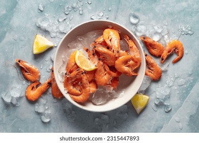 Healthy food. Fresh shrimps with ice on plate on light background top view