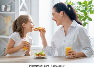 Healthy food at home. Happy family in the kitchen. Mother and child daughter are having breakfast. - Shutterstock ID 1180031134